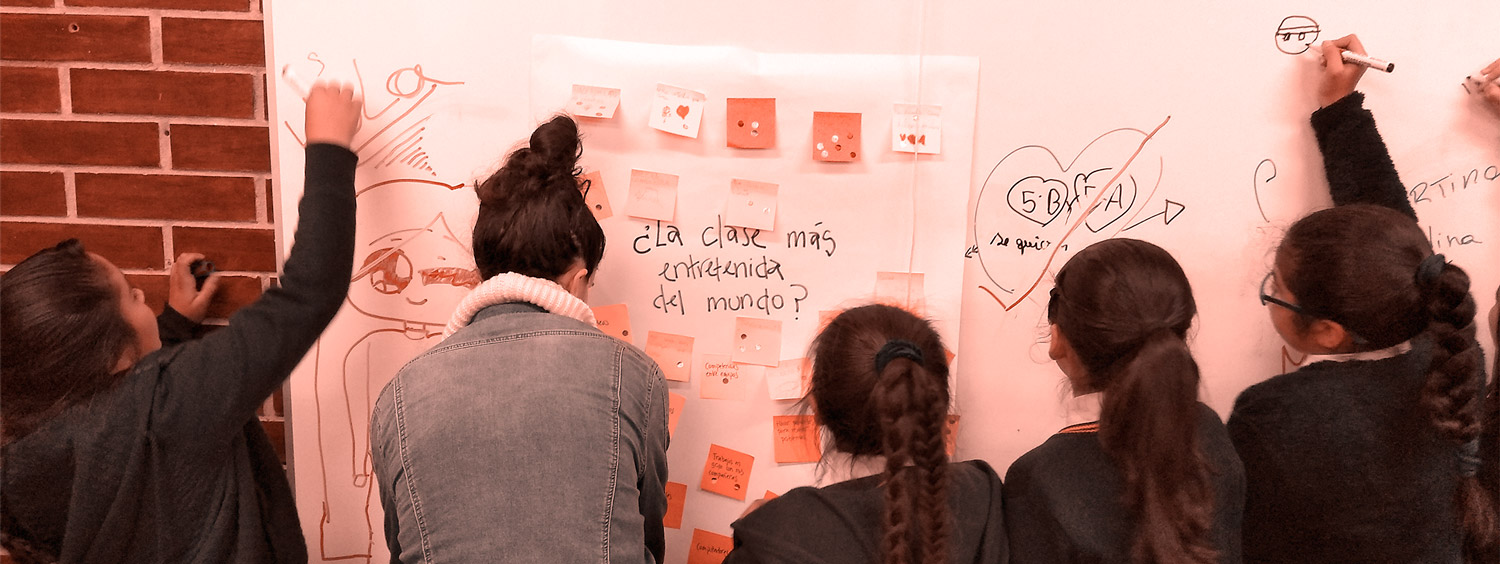 El siglo XXI exige un cambio en la educación. Niñas junto a su profesora dibujando y escribiendo en el pizarrón.