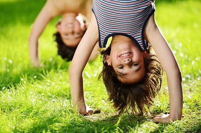 Día Mundial del Juego. Niños en posición invertida jugando en el pasto.