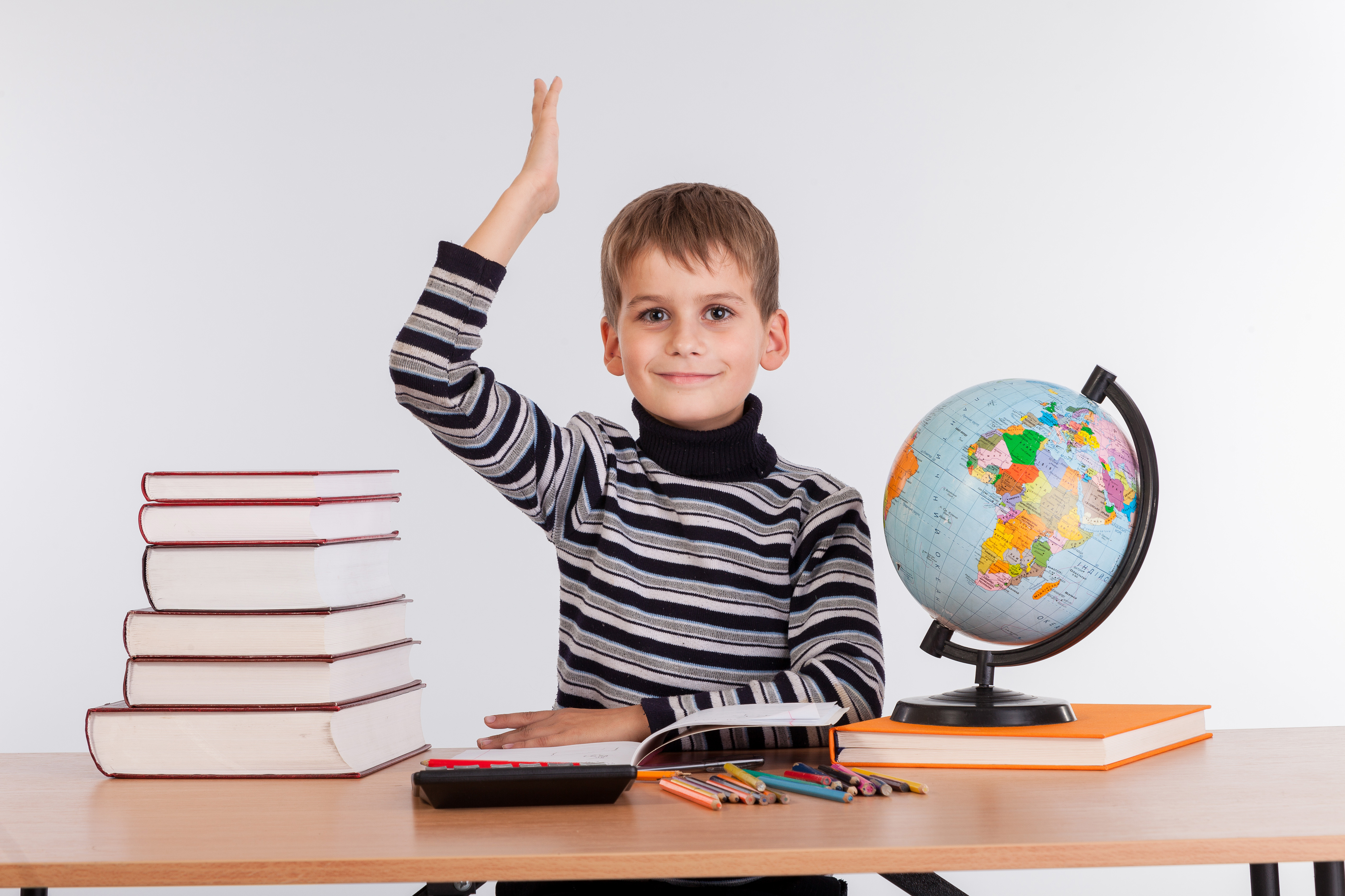 geografía La imagen muestra a un niño con libros, lápices y globo terraqueo