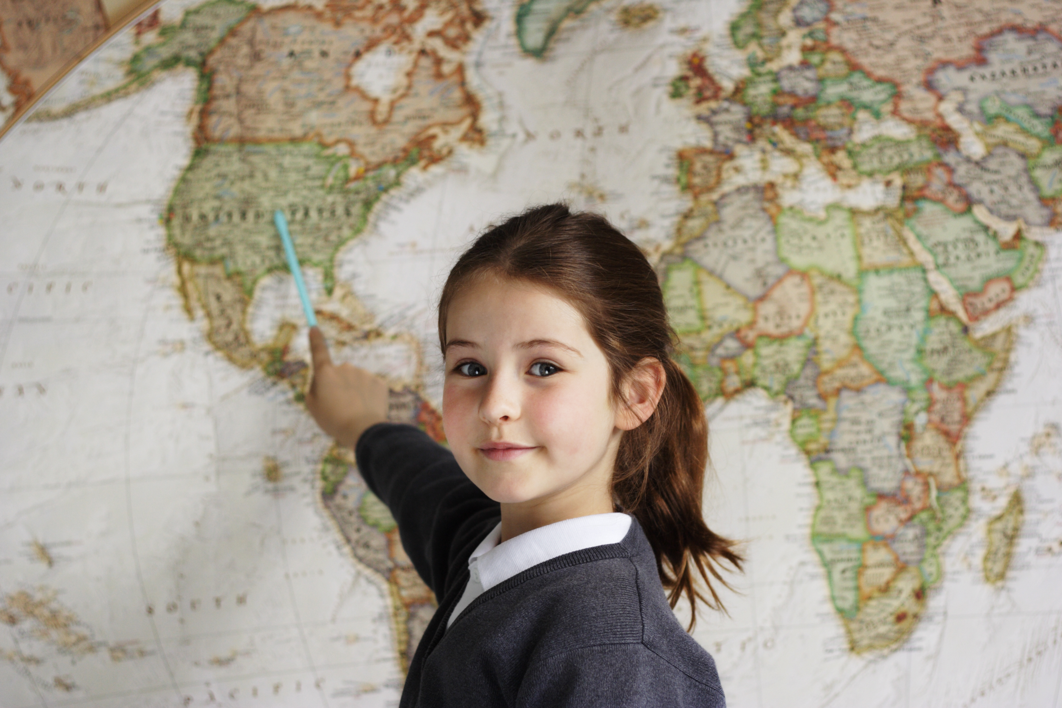 La imagen muestra a una niña apuntando un mapa 