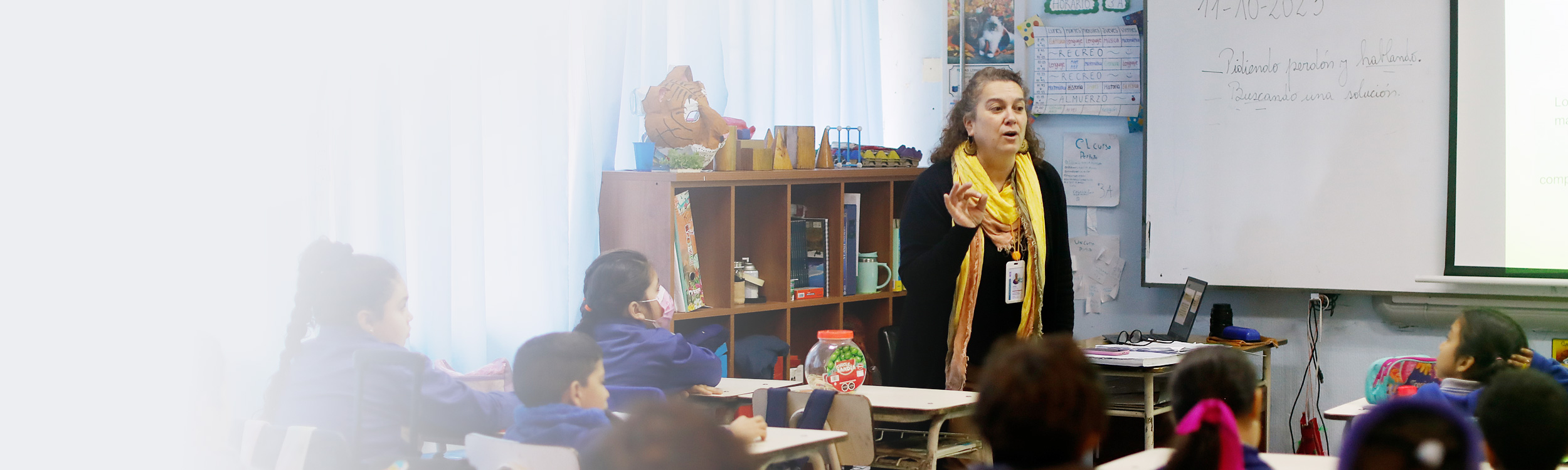 Fotografía de docente enseñando a estudiantes en sala de clases.