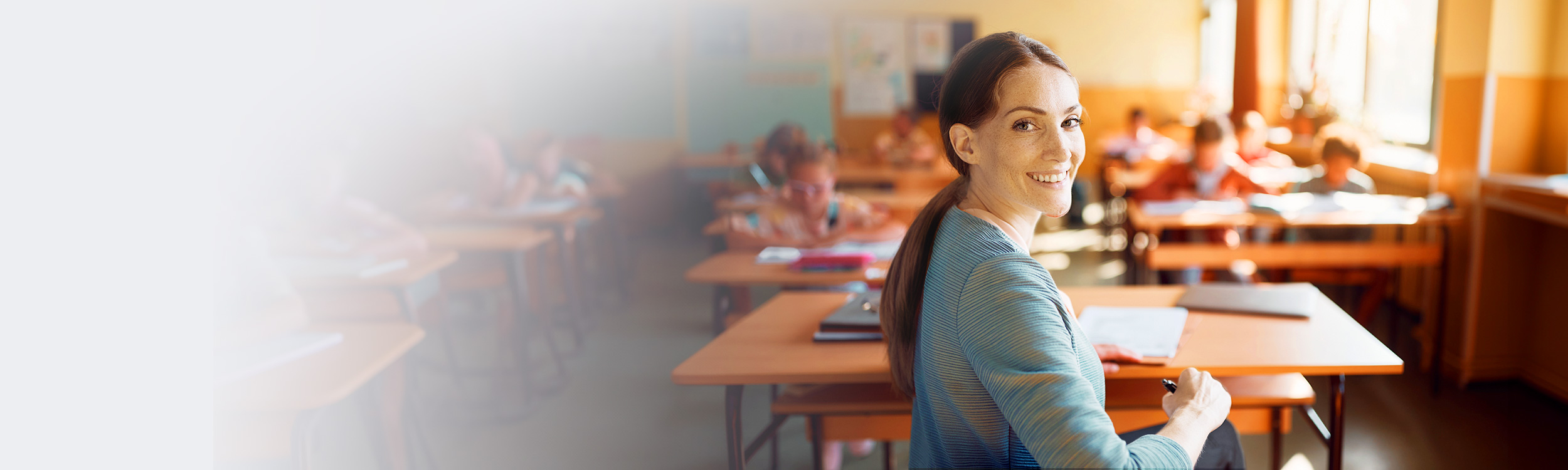 Fotografía de docente en sala de clases, sonriendo a la cámara.
