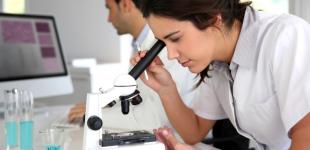 La imagen muestra a una mujer mirando por un microscopio