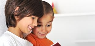 Dos niños pequeños leen un libro 