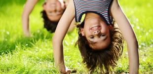 Día Mundial del Juego Niños en posición invertida jugando en el pasto.