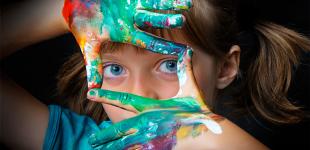 La imagen muestra una niña con las manos pintadas