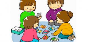 niñas y niños sentados en círculo jugando cartas