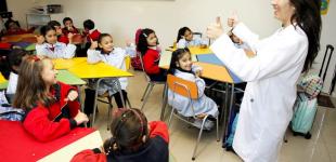 Profesora habla a sus estudiantes sentados en el aula