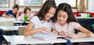 Dos mujeres adolescentes comparten la lectura de un libro alegremente