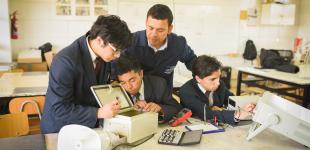 Tres alumnos trabajan junto a su profesor en el desarrollo de una alarma barrial
