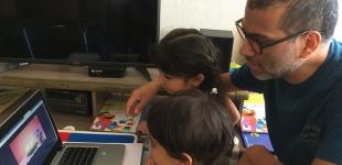 Padre y sus hijos pequeños viendo una película educativa online