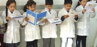 La imagen muestra un grupo de estudiantes de pie leyendo al curso un fragmento de un libro de trabajo