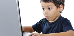 La imagen muestra a un niño sorprendido observando algo en un notebook