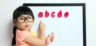 La imagen muestra a una niña indicando unas letras en una pizarra