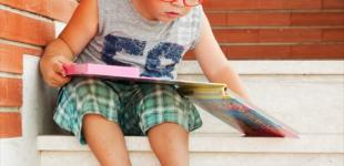 La imagen muestra a un niño observando un libro 