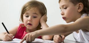 La imagen muestra a una niña y un niño miran contenido en un libro