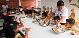 La imagen muestra a niños y niñas recibiendo su alimentación