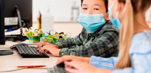 Dos niños en clase frente a un computador 