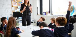 Profesora en la sala junto a sus estudiantes participando en clases