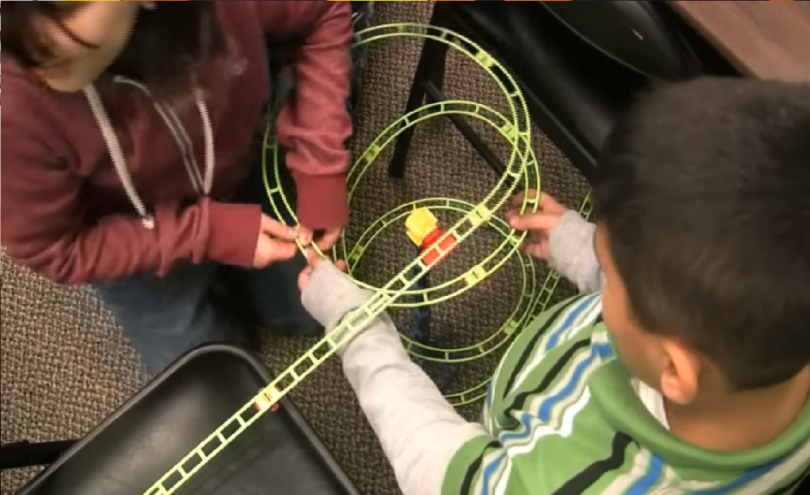 Niños construyen una estructura con rieles de plástico