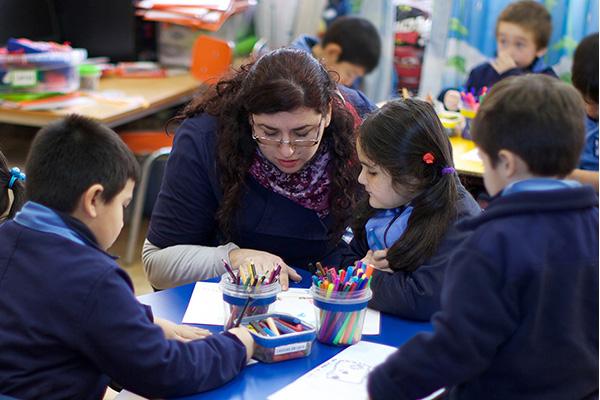 Profesora apoyando a sus estudiantes en una investigacion.
