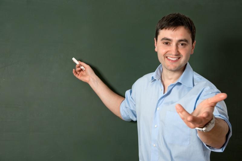 Imagen de un profesor sonriendo y escribiendo en un pizarrón.