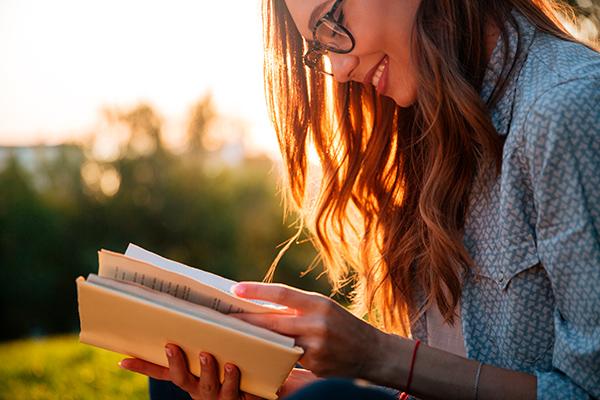 Mujer joven leyendo un libro al aire libre