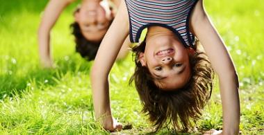 Niños en posición invertida jugando en el pasto. 