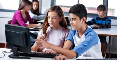 Imagen de una pareja de estudiantes que trabajan en un computador compartido.