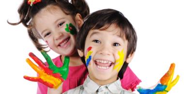 Imagen de una niña y un niño felices, con las manos y caras pintadas de colores.