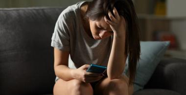 mujer mira un teléfono celular con angustia