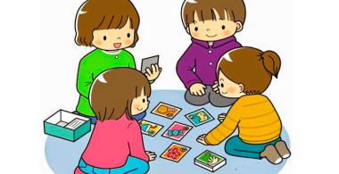 niñas y niños sentados en círculo jugando cartas