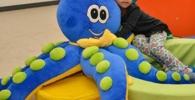 La imagen muestra a una niña jugando con un peluche en forma de pulpo
