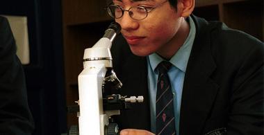 La imagen muestra a joven mirando un microscopio