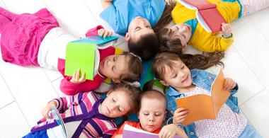 La imagen muestra un grupo de niños y niñas mirando libros