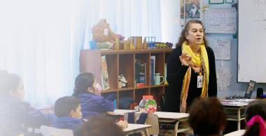 Fotografía de docente enseñando a estudiantes en sala de clases.